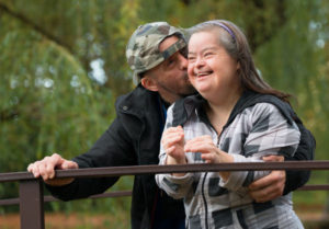 Couple with developmental disabilities kissing on bridge
