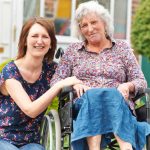 Image of support worker kneeling down next to woman in a wheelchair