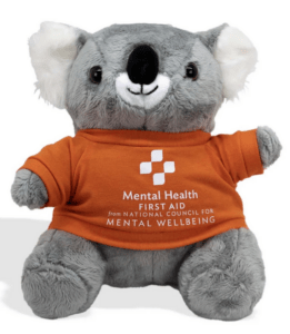 A picture of a Koala bear wearing an orange shirt that says "Mental Health First Aid from the National Council for Mental Wellbeing"